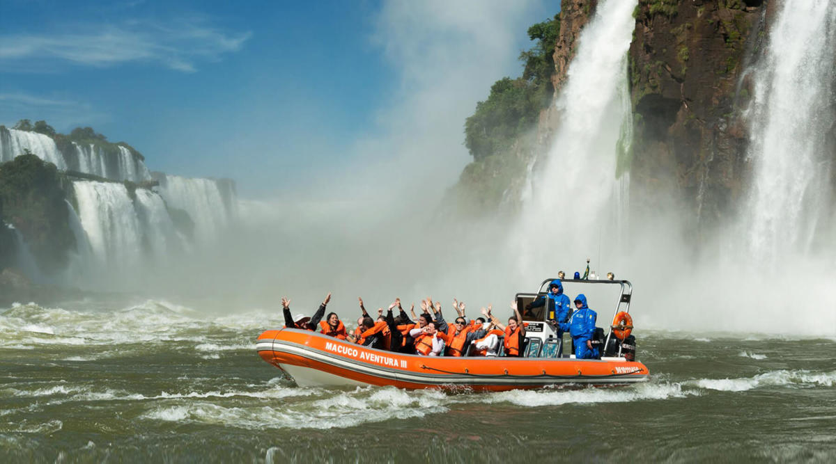 A boat with visitors in life jackets approaching the base of the Iguazu Falls