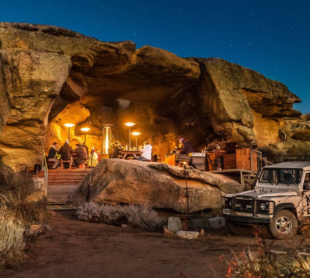 Warmly lit cave shelter built under a sandstone overhang on the cliffs above Lago Argentino, Patagonia