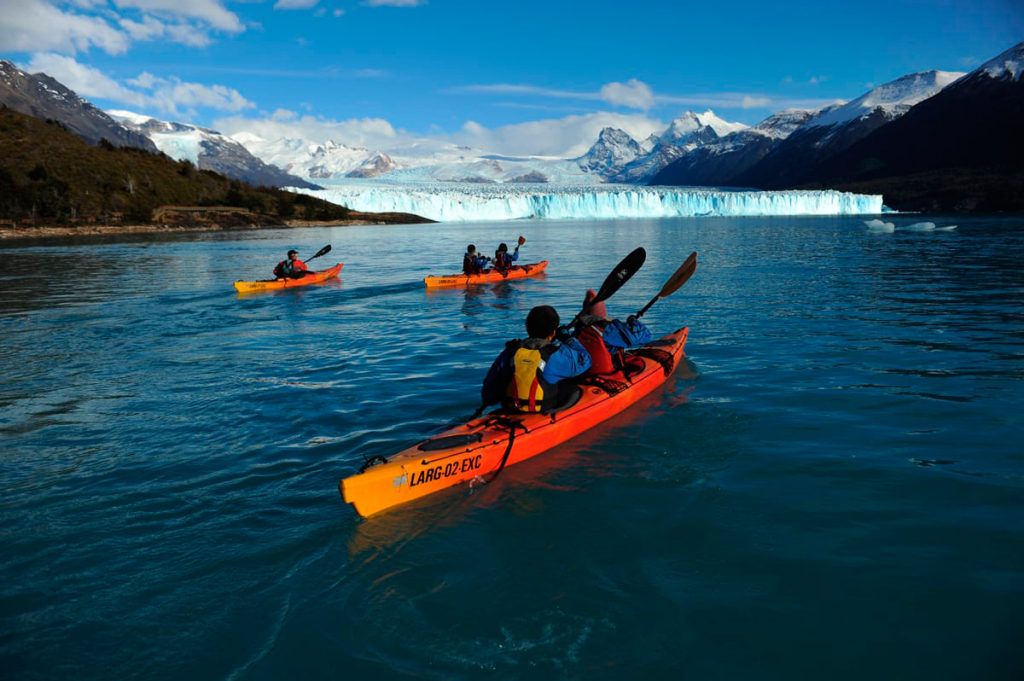 Group of sea kayaks paddling on Lago Argentino with the Perito Moreno Glacier and the Andes behind