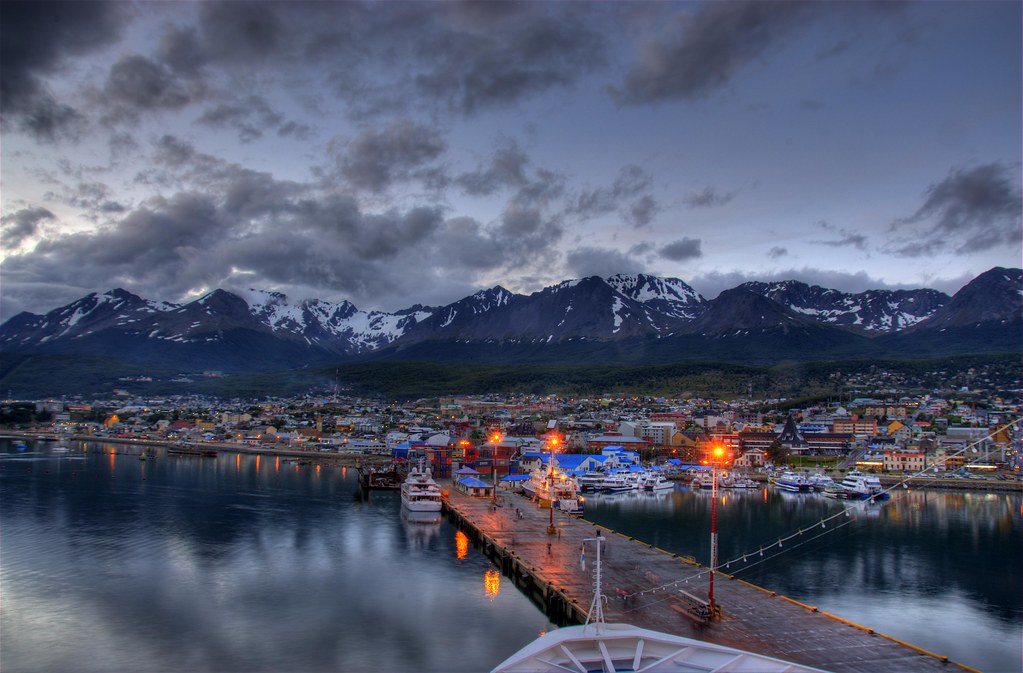 The port of Ushuaia at dusk, with the pier lit up and the mountains behind