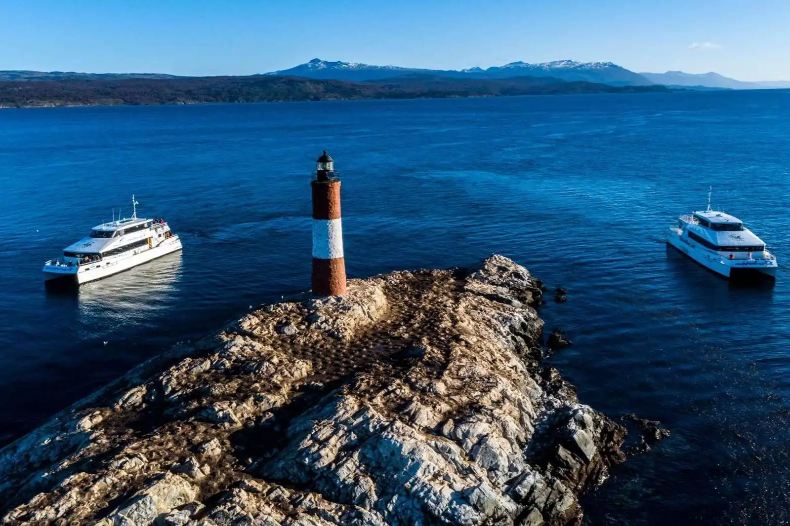 Aerial view of the Les Eclaireurs lighthouse on its islet with catamarans in the Beagle Channel