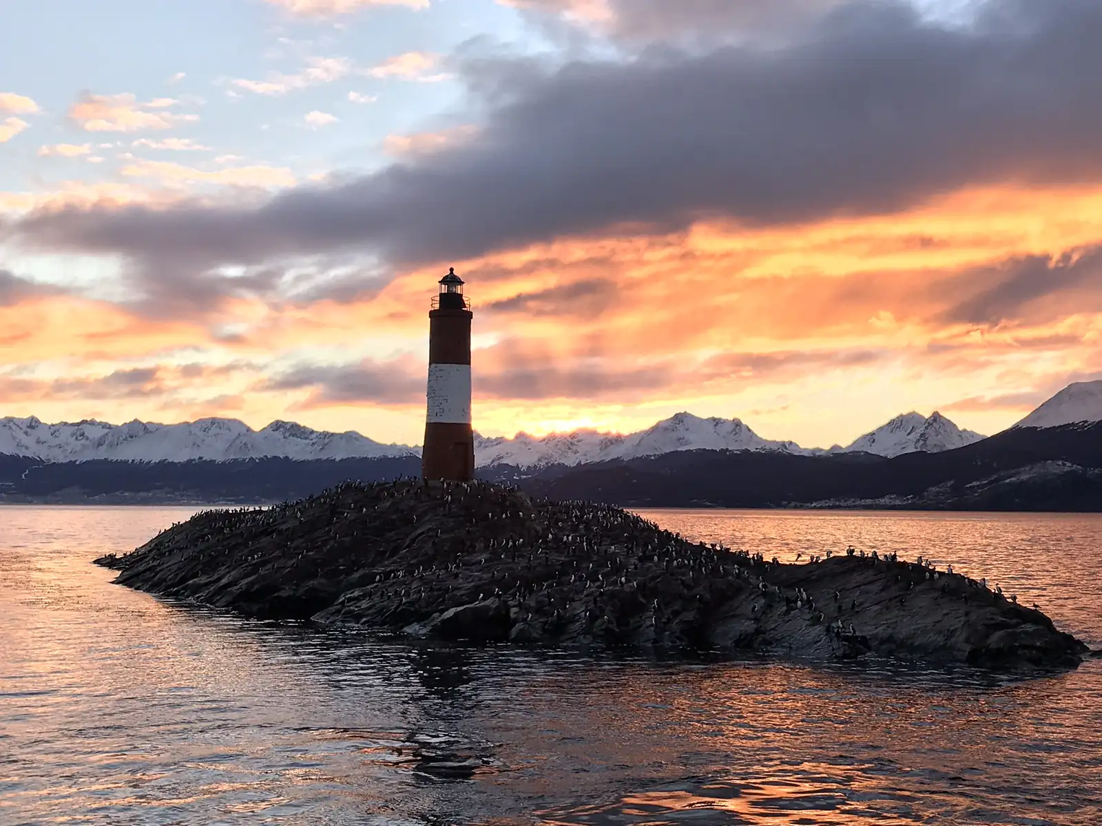 The Les Eclaireurs lighthouse silhouetted against a sunset over the Beagle Channel