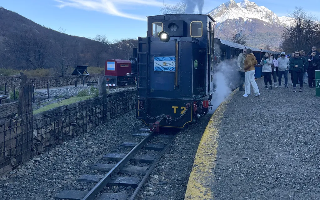 The steam locomotive of the End of the World Train arriving at the platform with a snow-covered peak behind it, Ushuaia