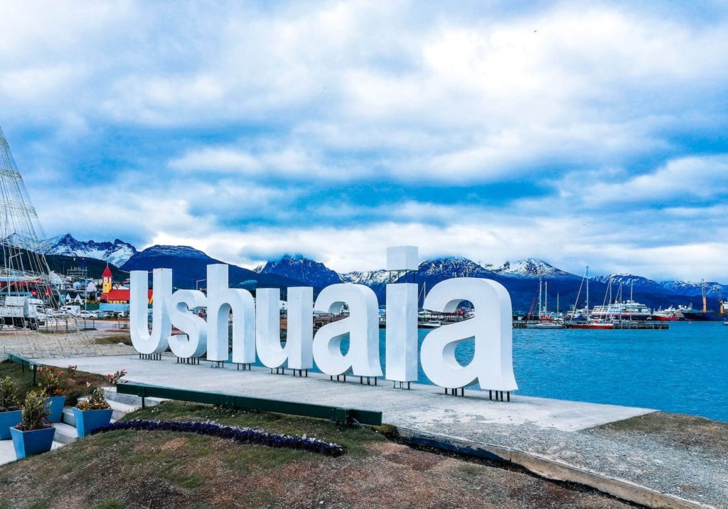 The Ushuaia sign by the port, with the bay and the Martial range behind it