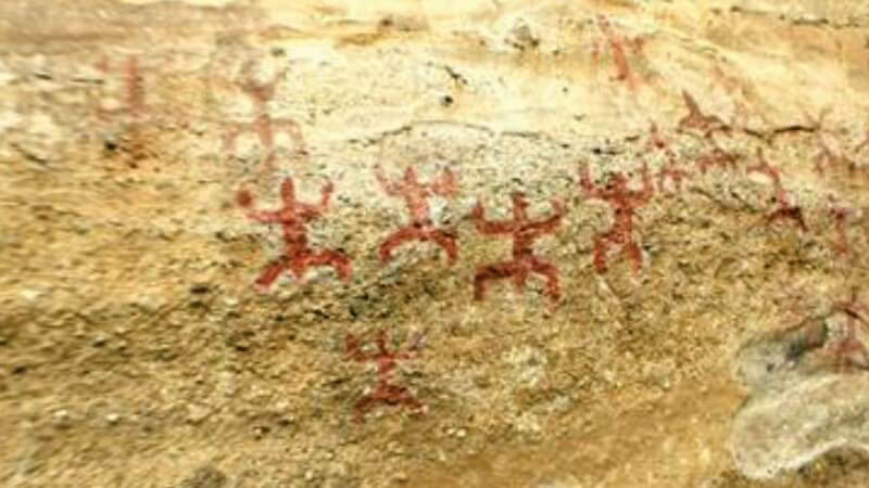 Ochre rock art figures painted on a pale sandstone wall at Punta Walichu, El Calafate